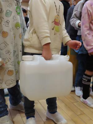 水の入ったタンクの重さを体験する園児