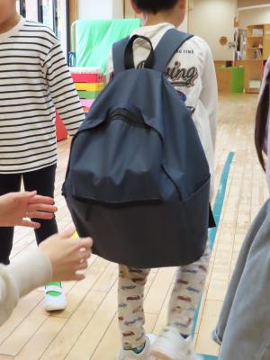 水の入ったペットボトルが入っているリュックサックの重さを体験する園児