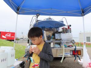 給水車の水を飲む子どもの写真